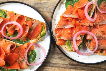Delicious toasts with smoked salmon, avocado and basil leaves