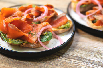 Delicious toasts with smoked salmon, avocado and basil leaves