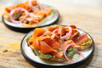 Delicious toasts with smoked salmon, avocado and basil leaves
