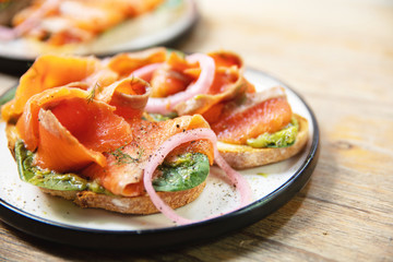 Delicious toasts with smoked salmon, avocado and basil leaves
