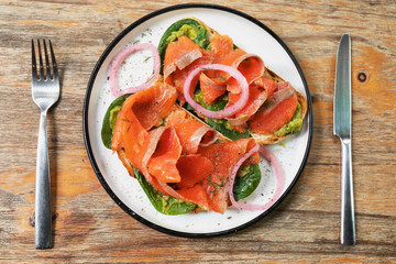 Delicious toasts with smoked salmon, avocado and basil leaves