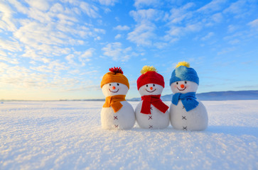Friends snowman in red, blue, yellow hats and scarfs. Nice winter scenery with mountains, field in...