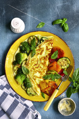 Omelette stuffed with green vegetables (broccoli, zucchini, spinach) garnished with grilled bell pepeer.Top view.