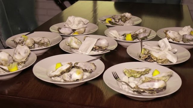 Dirty plates with empty oyster shells on a wooden table in the restaurant. leftovers after lunch. Eating food and cleaning dishes concept
