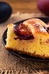 Portion of homemade cake with plums, close-up, vertical frame.