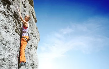 Rolgordijnen young slim female rock climber climbing on the cliff © vitaliymateha