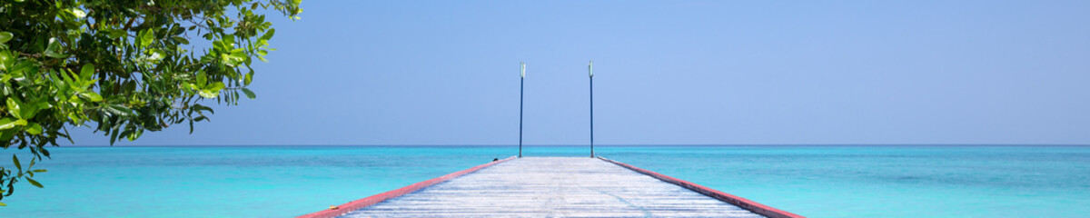 Fototapeta na wymiar Tropical travel destinations with Maldives island and wooden wharf