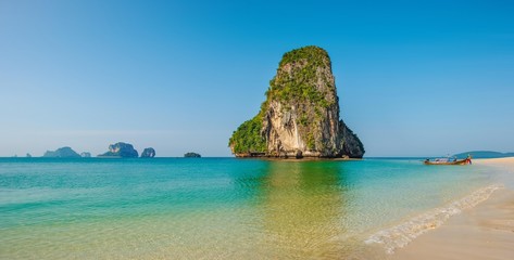 Fototapeta premium Panoramic view of idyllic Thailand beach with rock islands and a traditional longboat