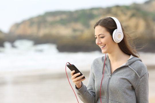 Teenage girl listening to music on the beach