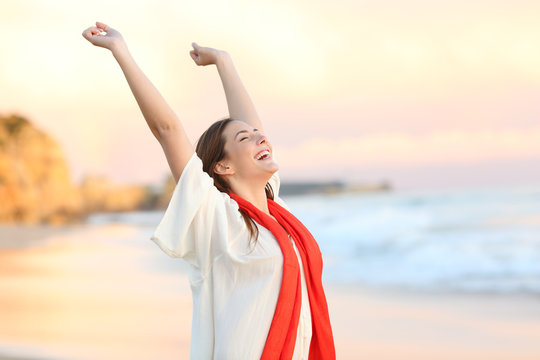 Excited woman celebrating sunset raising arms