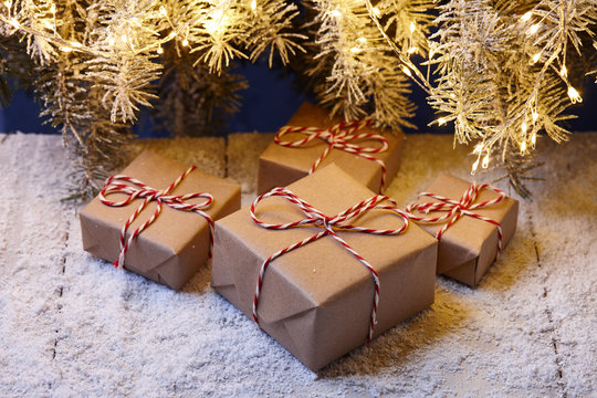 Christmas gift boxes wrapped in kraft paper under fir tree