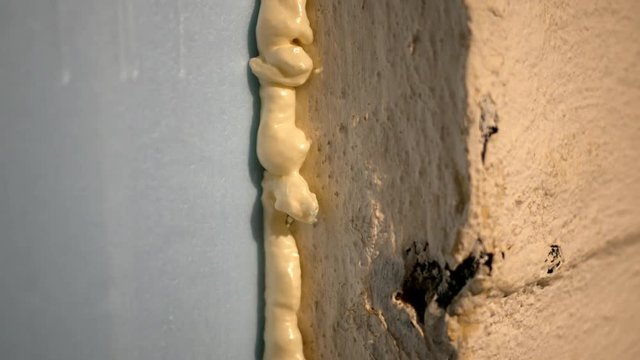 Yellow spray foam insulation in unfinished basement by blue board