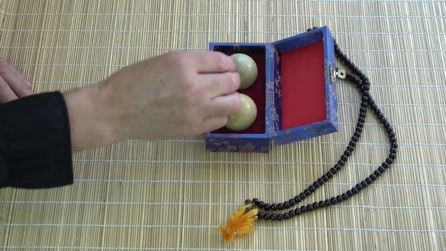 Opening box with Asian chinese hand massage marble balls  and Buddhist rosary on bamboo mat