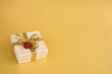 Fototapeta na wymiar Gift or present box with golden ribbon and Christmas decoration on yellow background. Top view, copy space. Christmas background.