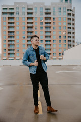 Young Trendy Male Fashion Model in Denim Jacket on Top of a Downtown Parking Garage