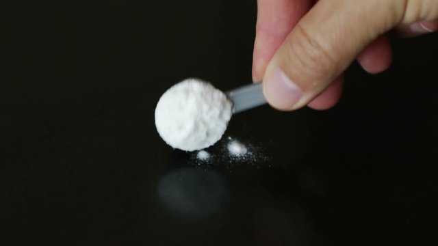 A man pours a measuring glass of a portion of protein, amino acids, glutamine bcaa.