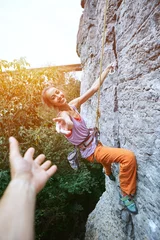 Foto op Plexiglas young slim female rock climber climbing on the cliff and getting help © vitaliymateha