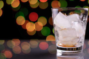 Empty Glass With Ice And Coffee Residue On A Shiney Platform With Dark Background And Colorful Bokeh Lights