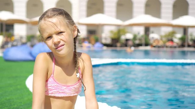 Beautiful little girl having fun near an outdoor pool