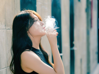 Portrait of beautiful Chinese girl smoking outdoor and thinking about problems, seems a little bit...
