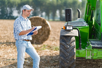 Farmer writing on a document on the field