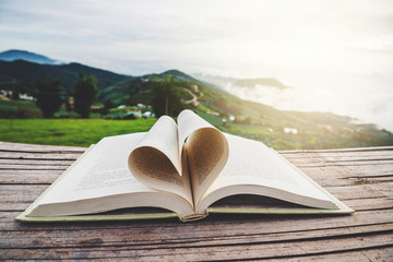 The book rests on a wooden balcony. Mountain view, mountain village, close up heart shape from...