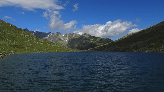 Time lapse view on peak of mountains and lake in Swiss Alps. Summer landscape, sunshine weather, blue sky and sunny day