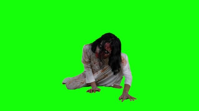 Scary undead zombie woman with wounded face crawling in the studio, shot in 4k resolution with green screen background