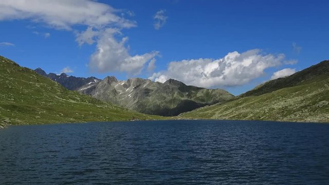Time lapse view on peak of mountains and lake in Swiss Alps. Summer landscape, sunshine weather, blue sky and sunny day