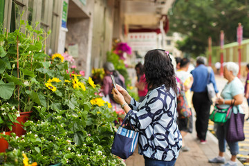 Woman taking photo with cellphone on flower market