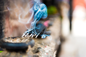 Burning incense sticks as religious offerings at temple in Nepal. Incence sticks over blurred background.