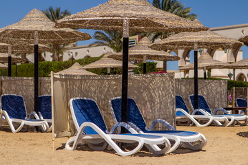 Two sun loungers under an umbrella on the sandy beach. view from the sea.