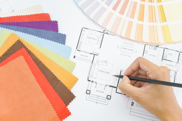 architects hands drawing of modern house with colors and material samples on creative desk