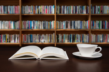 a book open on the desk with a cup of coffee.