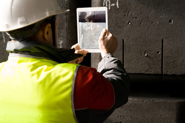 Back view portrait of modern factory worker wearing hardhat taking photo of codes while using...