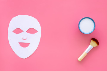 Cosmetic product for cleansing skin. Facial mask, cream and brush on pink background top view space for text