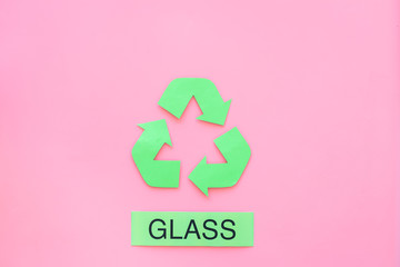 Types of matherial for reycle and reuse. Printed word glass near eco symbol recycle arrows on pink background top view copy space