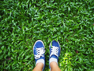 Selfie woman feet wearing blue sneaker on green grass