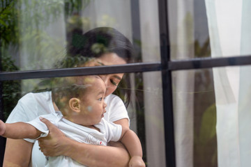 Asian Happiness family scene of mother Carry boy baby beside the windows in the house,Family Lifestyle Concept