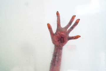 Bloody hand behind glass bathroom window