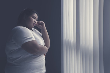 Fat woman thinking something by the window