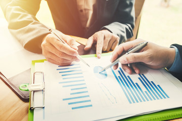 Hand of businessman holding the pen point to the graph information during discussion at meeting