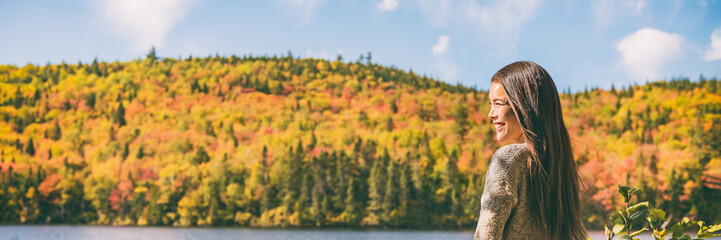 Fall forest Asian woman enjoying countryside cottage getaway. Canada autumn holidays banner panoramic of yellow foliage, forest colors.