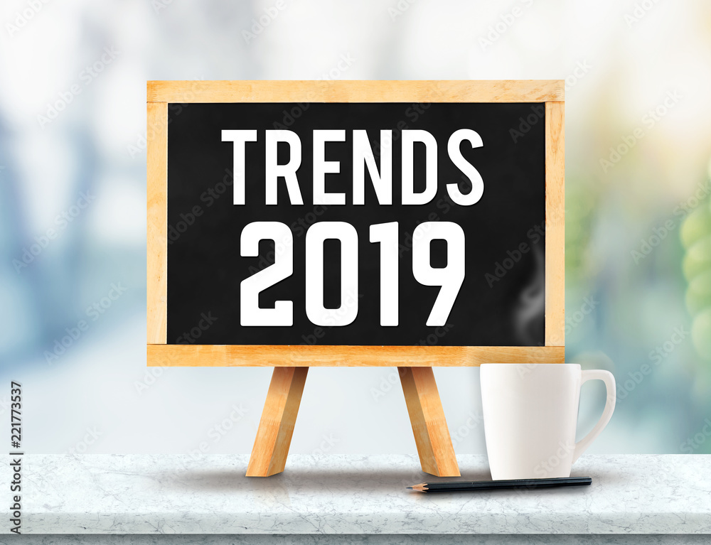 Poster Trends 2019 on blackboard with easel on marble table with sun and blur green tree bokeh background.business vision concept.