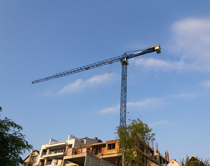 Crane and building construction site against blue sky. Urban construction