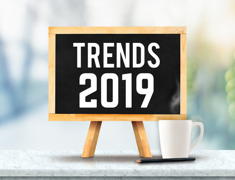 Trends 2019 on blackboard with easel on marble table with sun and blur green tree bokeh background.business vision concept.