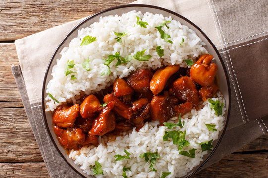 American food: Bourbon chicken in a sauce with whiskey, served with rice on a plate. horizontal top view