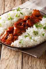 Louisiana food: bourbon chicken with garnish of rice close-up served on a plate. vertical, rustic