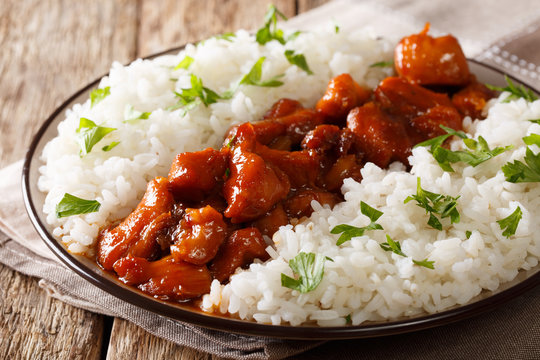 Stewed Bourbon chicken in sauce with whiskey, sugar, ginger and soy, served with rice on a plate. horizontal