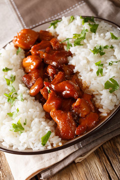 New Orleans bourbon chicken with garnish of rice close-up served on a plate. vertical